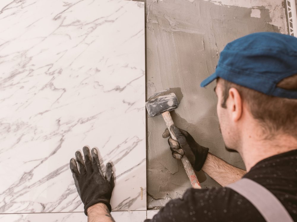 Handyman instaling ceramic tiles on the bathroom wall